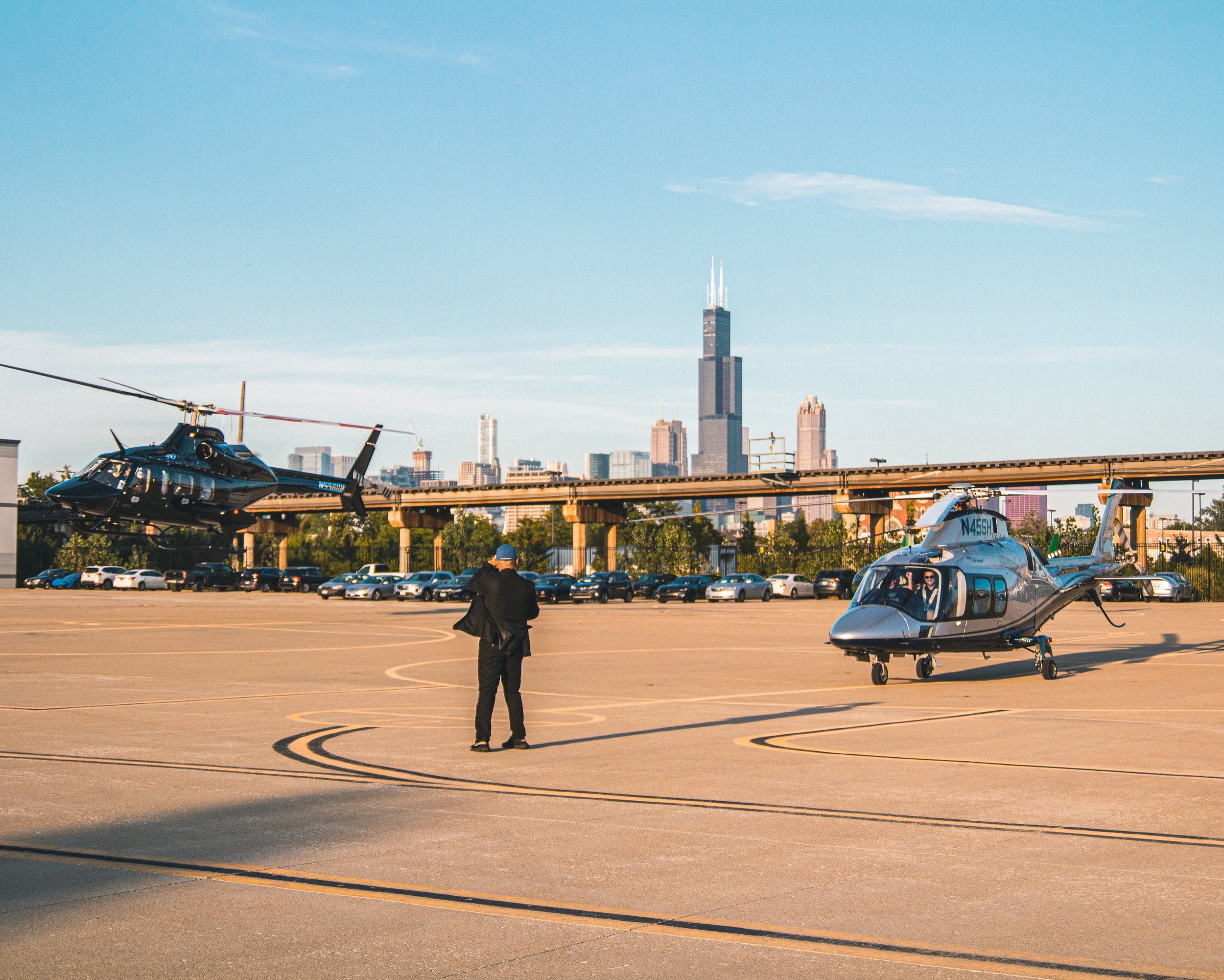 Helicopters on the pad at Vertiport Chicago with the downtown skyline at golden hour